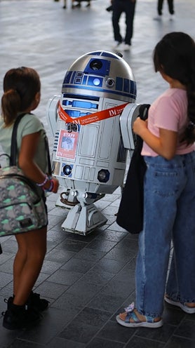 Imagen secundaria 2 - Arriba, dos visitantes junto a un Bansky, debajo un fan de 'Star Wars' fotografía una de las maquetas y dos niñas, junto a un R2D2.