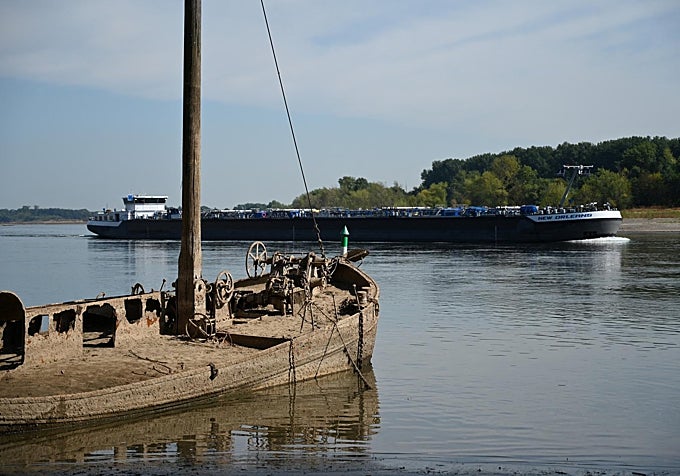 Un mercante navega por el centro del Rhin junto a un viejo barco semihundido.