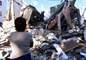 Una mujer observa a los equipos de rescate que buscan supervivientes entre los escombros de un edificio colapsado tras un terremoto en Pereira, Colombia.