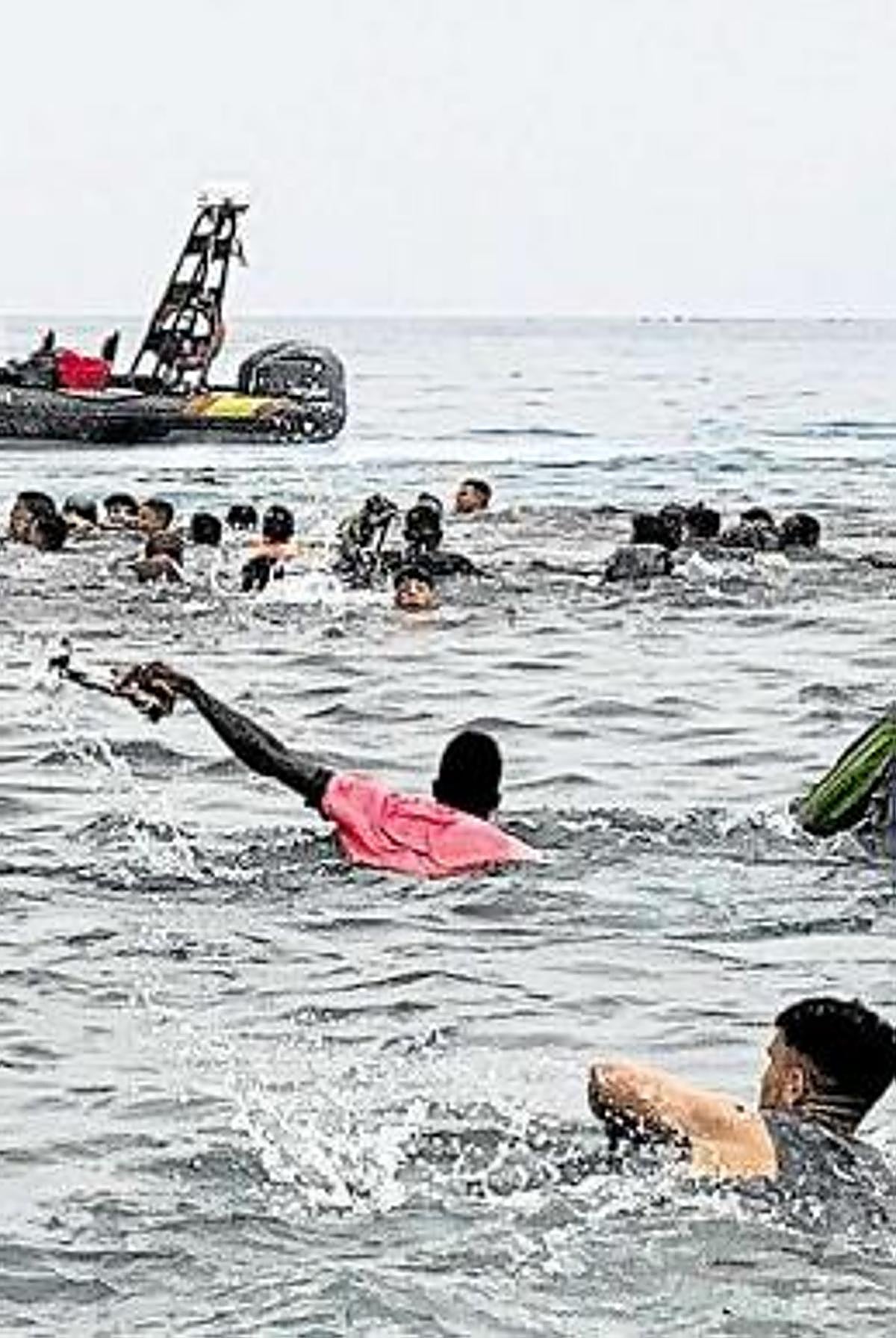 - Un grupo de personas tratan de llegar a nado desde la playa de la localidad de Fnideq (Castillejos, Marruecos) hacia uno de los espigones de Ceuta en mayo de 2021
