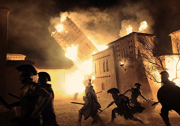Imagen principal - Arriba, un fotograma de la batalla de Troya; debajo, Christopher Nolan y Hoyte Van Hoytema, con la cámara IMAX, entre los extras, y Tom Holland como Telémaco.