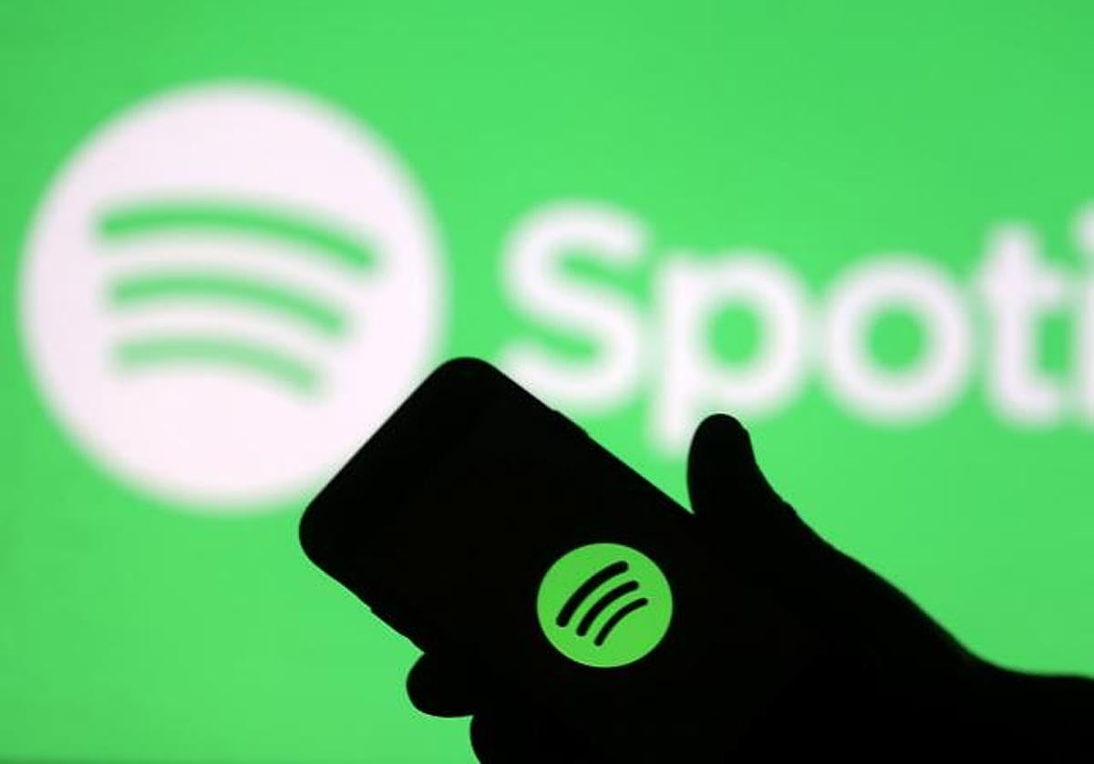 Un teléfono delante del logo de Spotify.