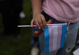 Una persona sostiene una bandera trans.