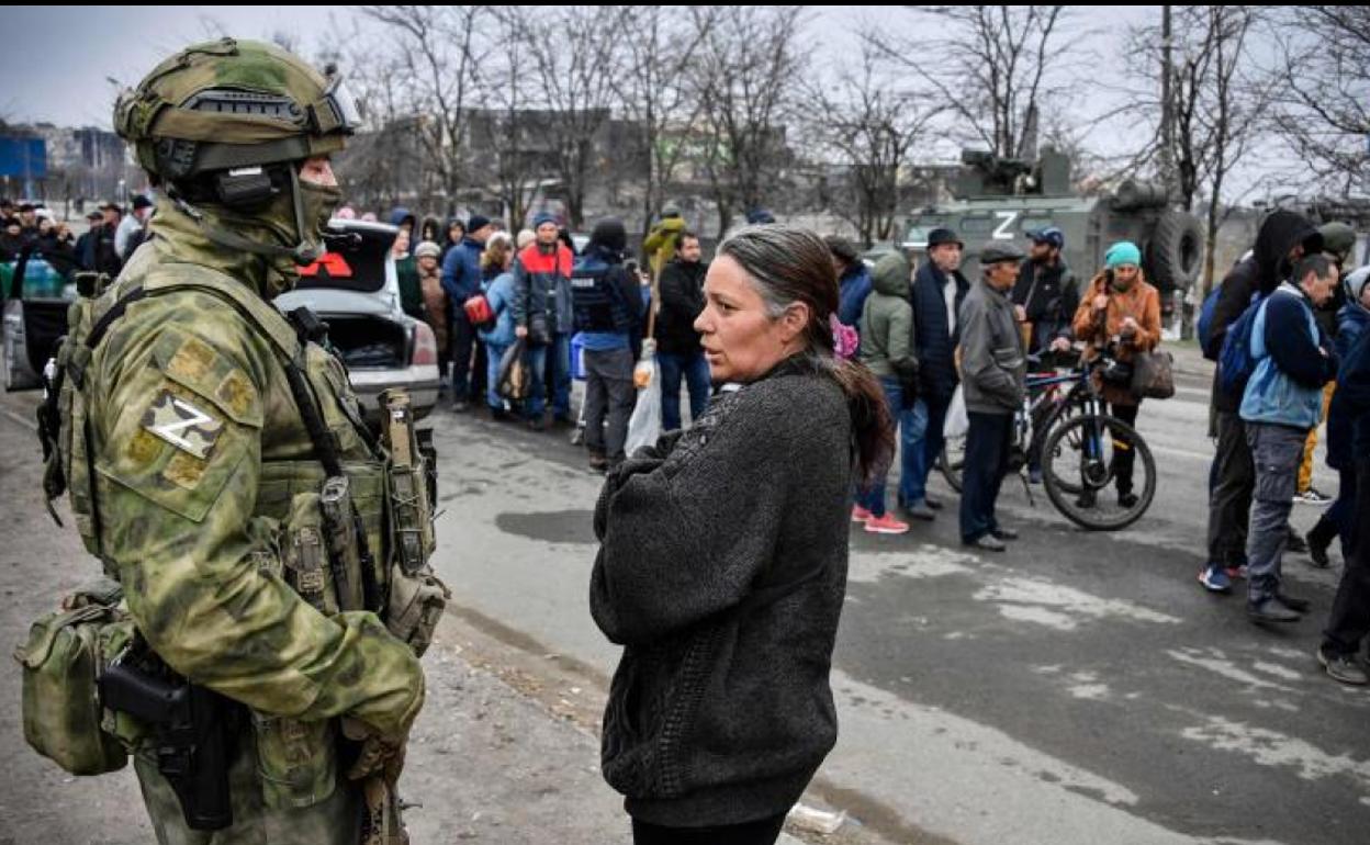 Sin provisiones. Una mujer se planta ante un soldado ruso mientras decenas de personas hacen fila en una distribución de alimentos organizada por el Ejército del Kremlin y voluntarios en la ciudad asediada de Mariúpol.