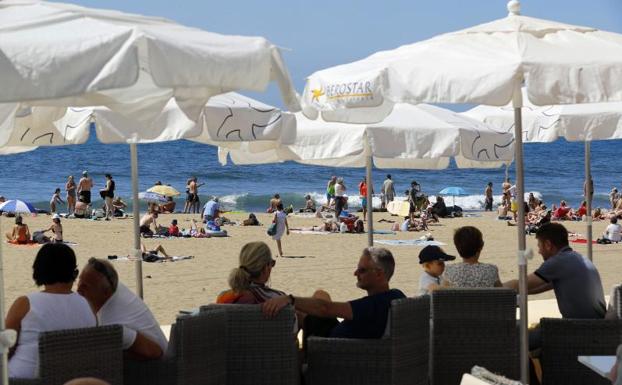 Turistas al sol y en terrazas en una playa de Maspalomas (Gran Canaria).