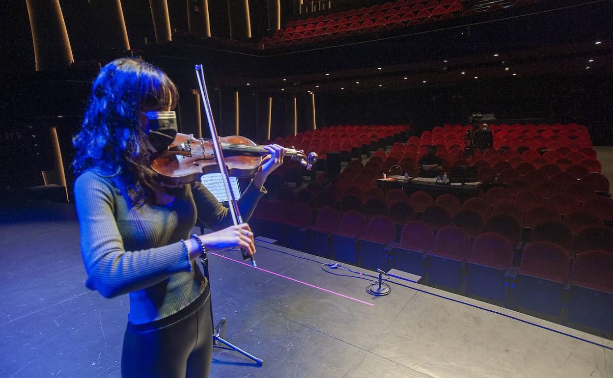 Una violinista interpreta una pieza sobre el escenario.