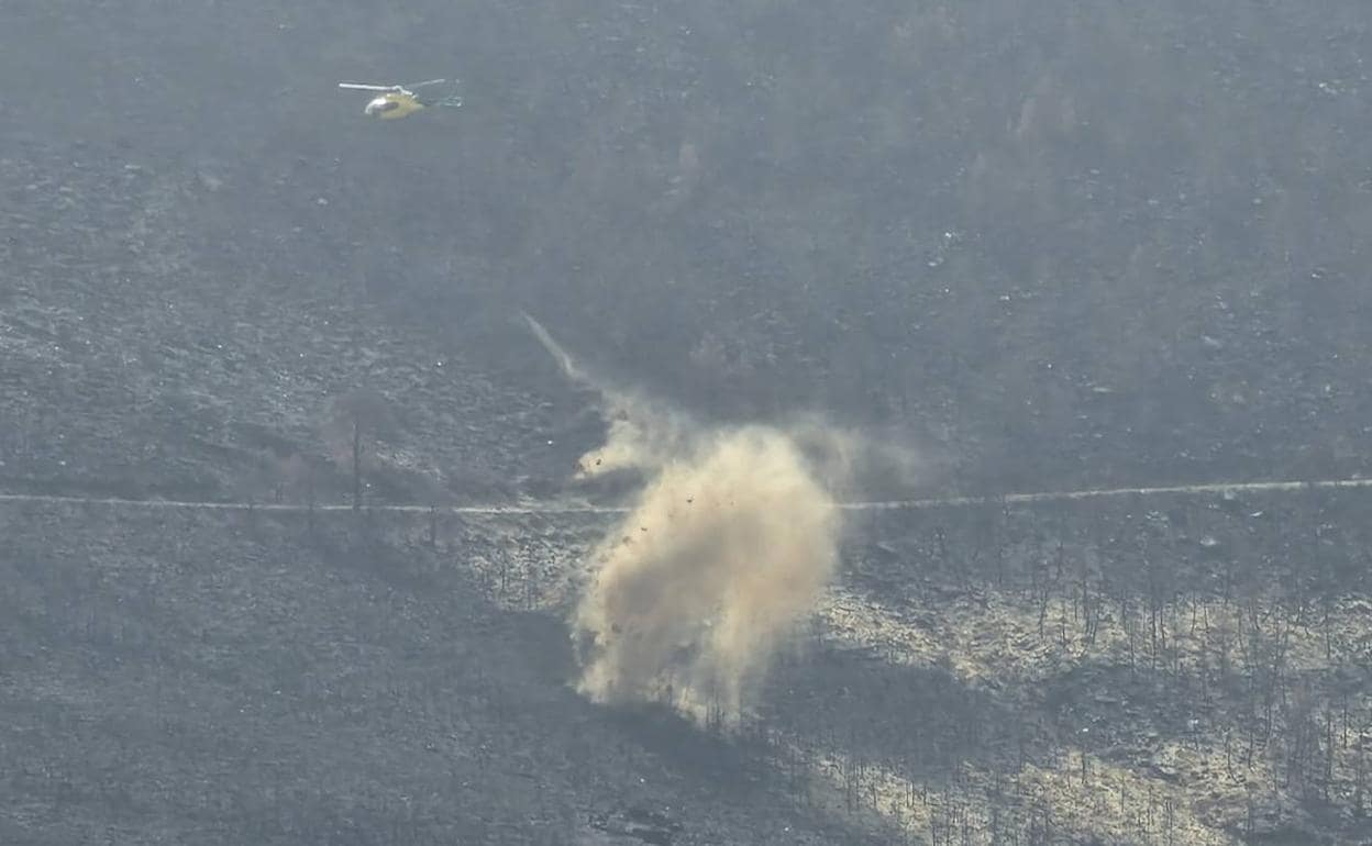 Un helicóptero lanza paja a una de las laderas quemadas en Monsagro. 