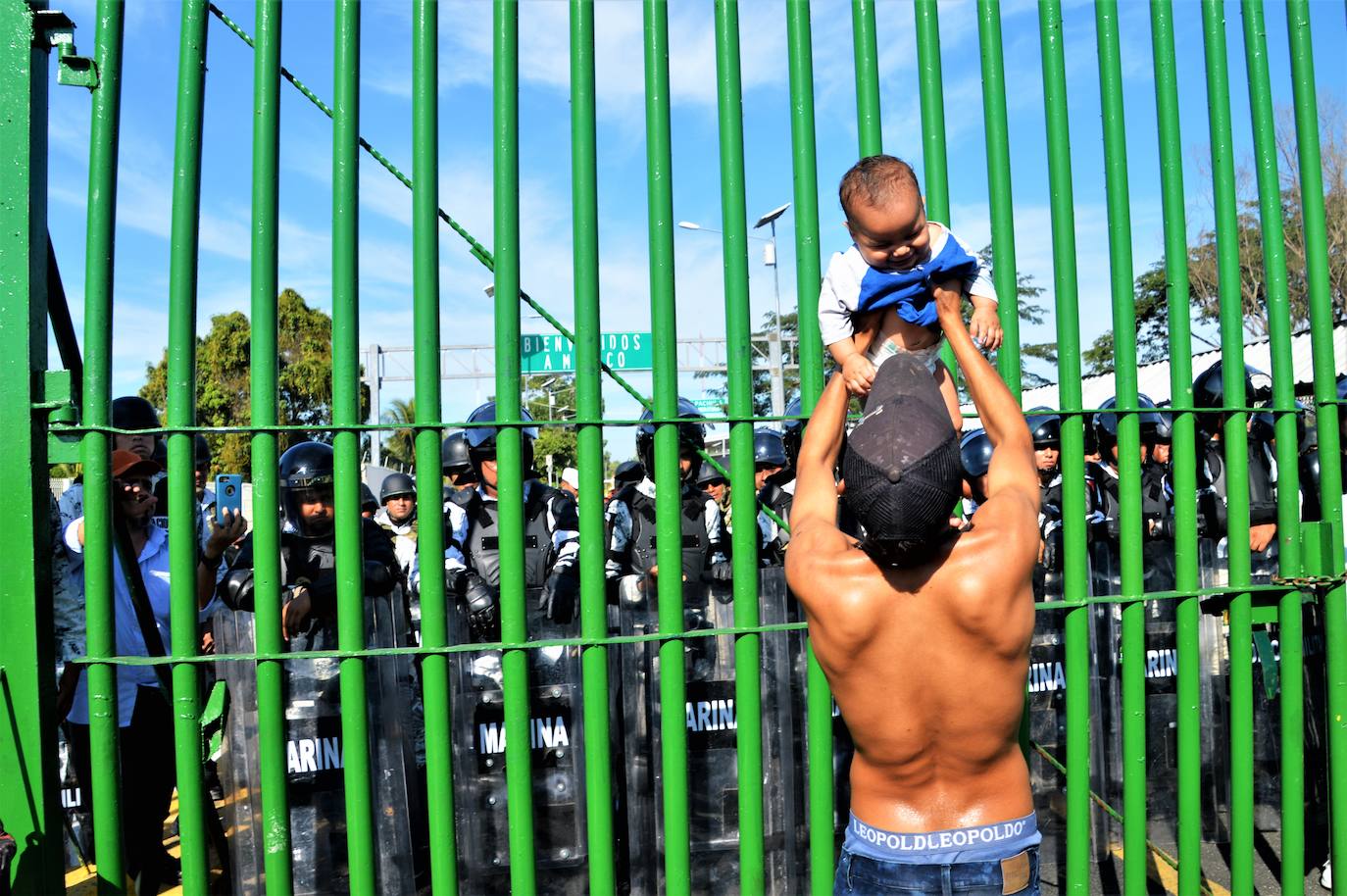 Un joven levanta a un bebé en el puente fronterizo Rodolfo Robles en Guatemala, donde la Guardia Nacional de México impide el paso a la caravana migrante que se dirige a EE UU en enero de 2020.