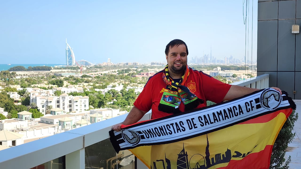Dani Mena posa con una bandera de España y la bufanda de Unionistas en Dubai. 