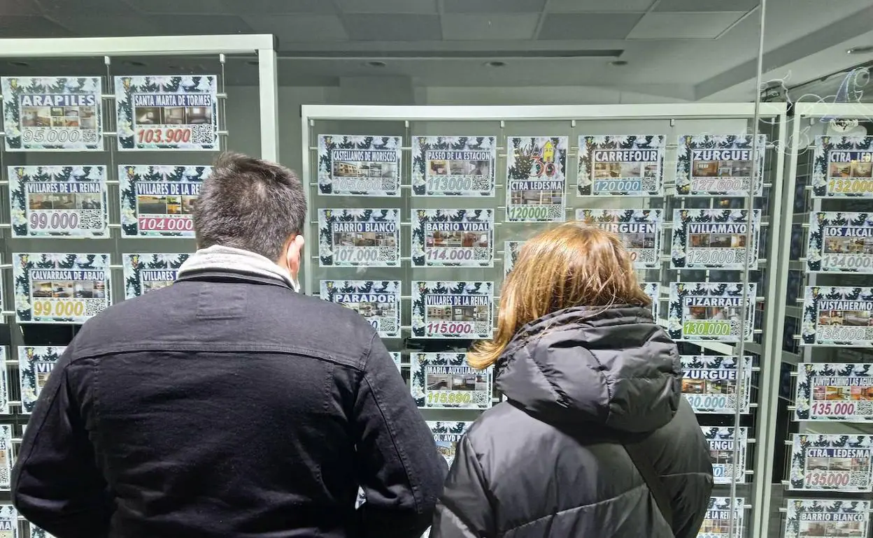 Dos personas observan las ofertas de una inmobiliaira.