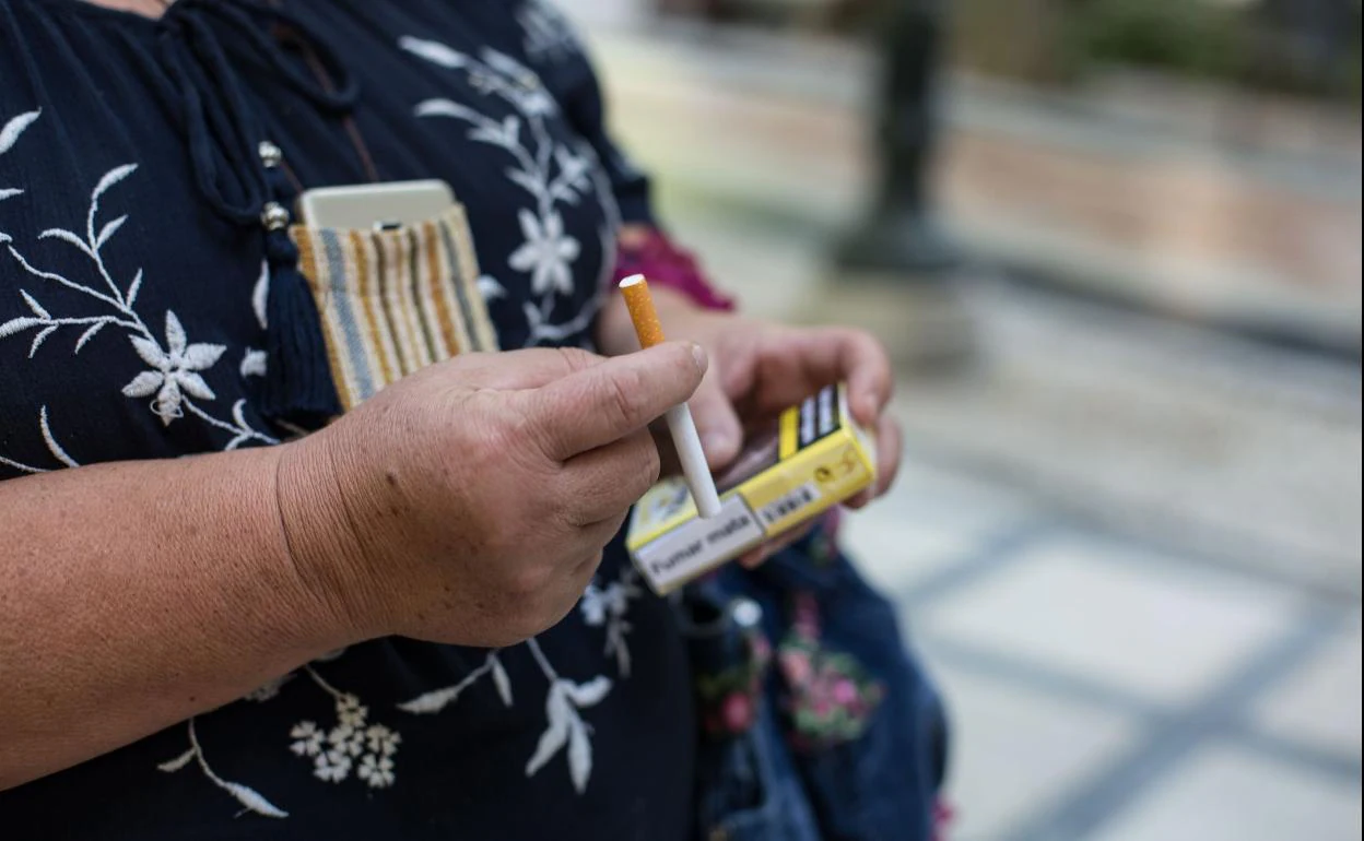 Una mujer sostiene un cigarrillo de tabaco. 