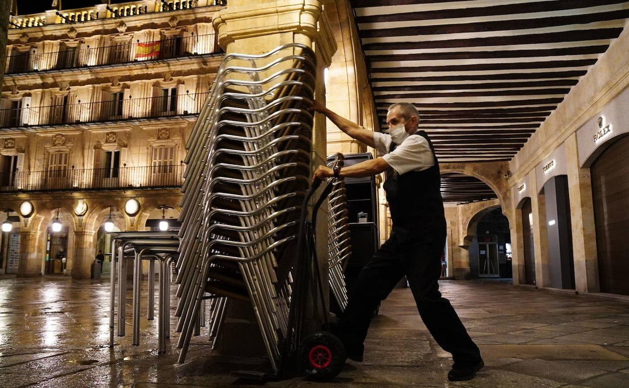 Un trabajador de la hostelería coloca las sillas. 