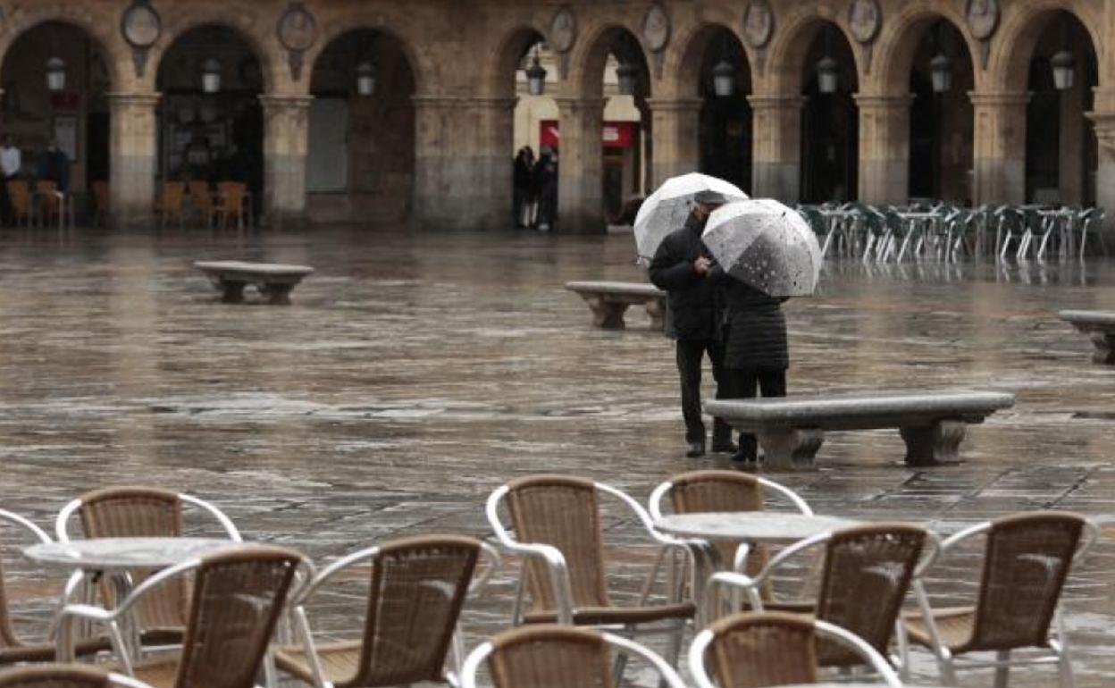 Una pareja de ancianos charlando bajo la lluvia en la Plaza Mayor de Salamanca.