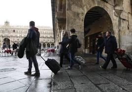 Un grupo de personas entra a la Plaza Mayor de Salamanca con sus maletas.