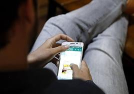 Un joven consulta en su móvil una aplicación de mensajería.