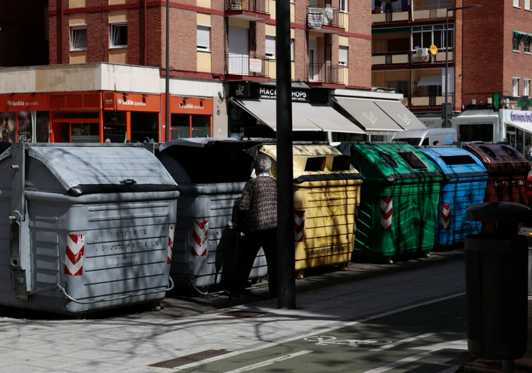 Una mujer deposita basuras en un contenedor gris de Garrido.