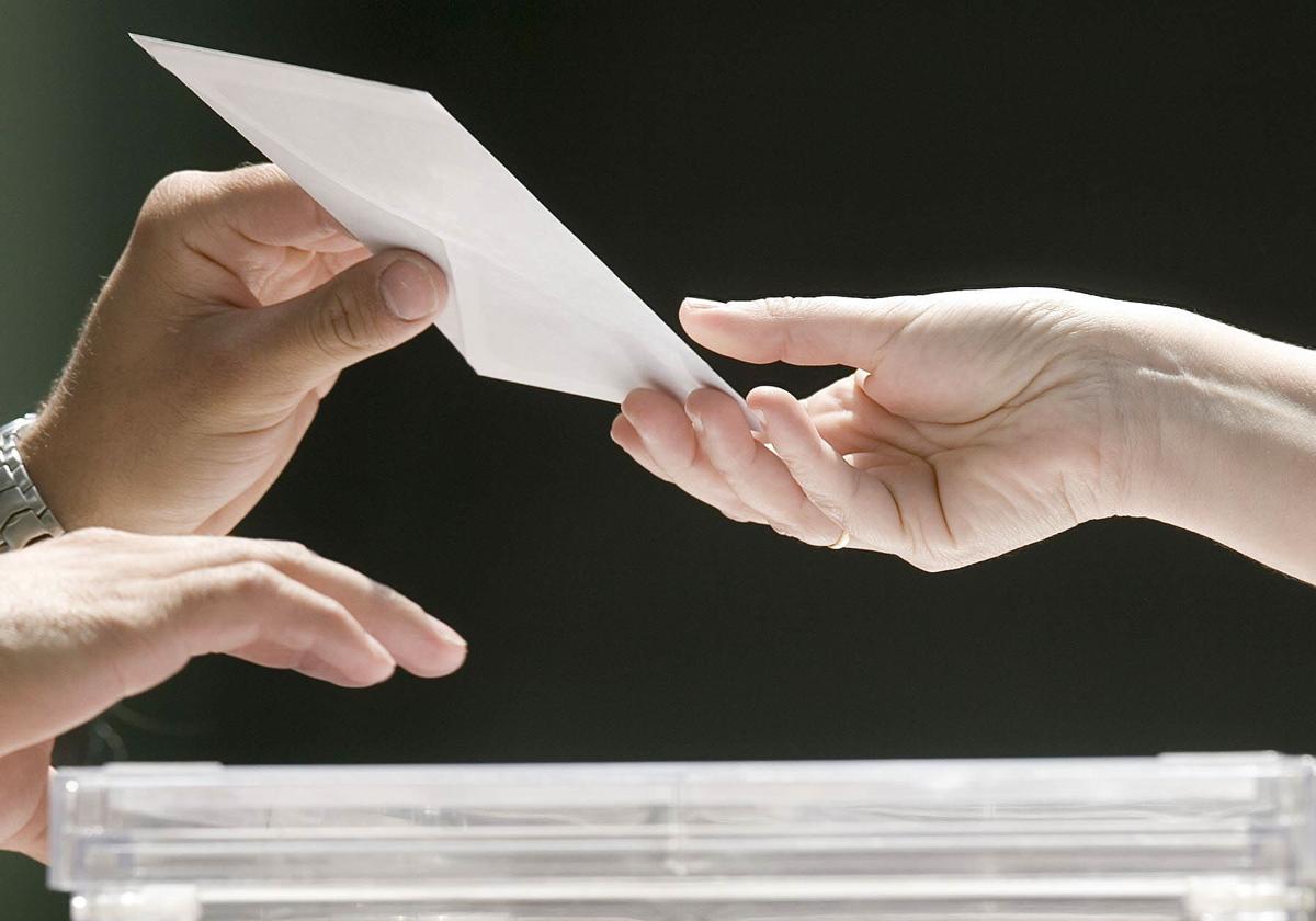 Una persona deposita su voto en una mesa electoral.