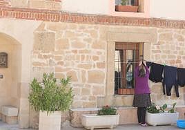 Una mujer tiende la ropa en la fachada de su casa.