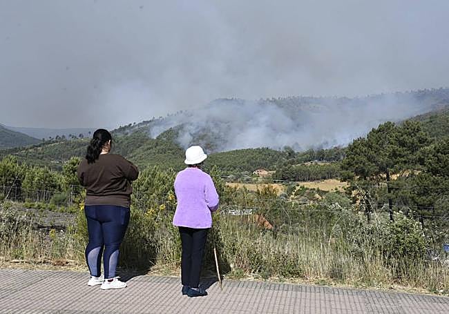 Dos mujeres observan el incendio a escasos metros de algunas casas.