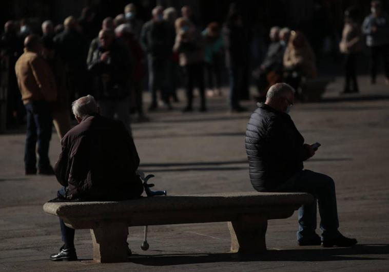 Dos personas, sentadas en un banco de la Plaza Mayor de Salamanca.