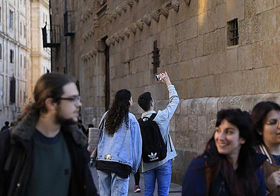 Una pareja graba con el móvil la fachada de la Casa de las Conchas.