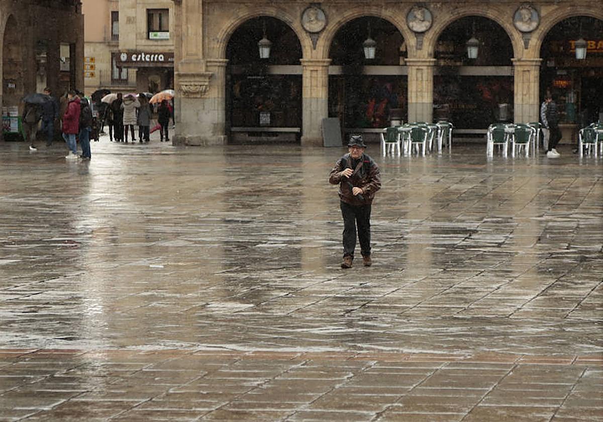 Un viandante caminando por una mojada Plaza Mayor de Salamanca producto de la lluvia.