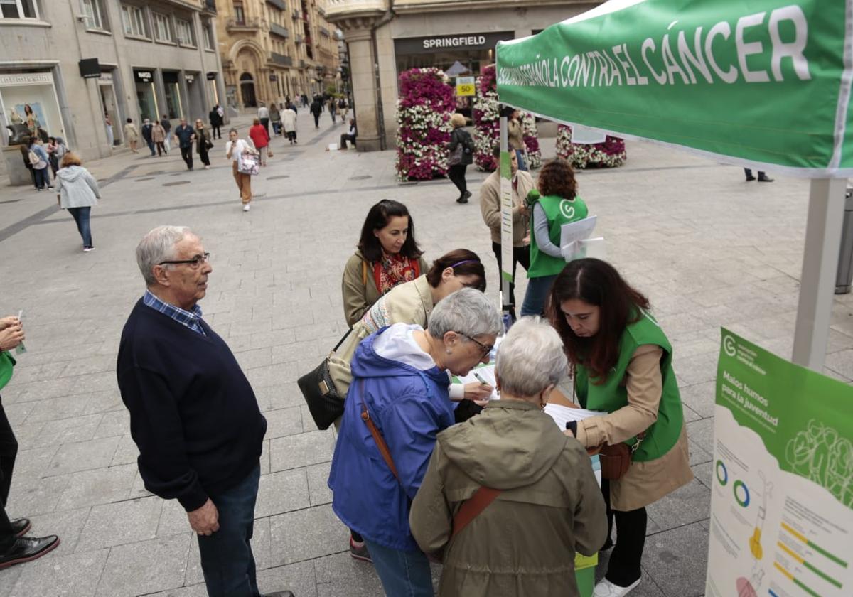 Varias personas firman en favor de la campaña de la Aecc.