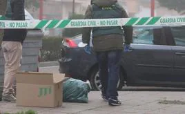 Agentes de la Guardia Civil en la calle en la que se produjo el suceso buscando ropa en los contenedores.