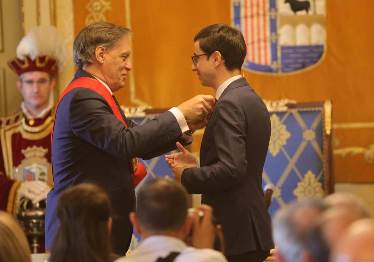 El alcalde pone medalla e insignia al líder de la oposición.