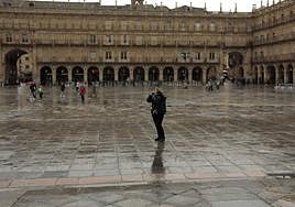 Un ciudadano pasea por la Plaza Mayor de Salamanca mojada por la lluvia.