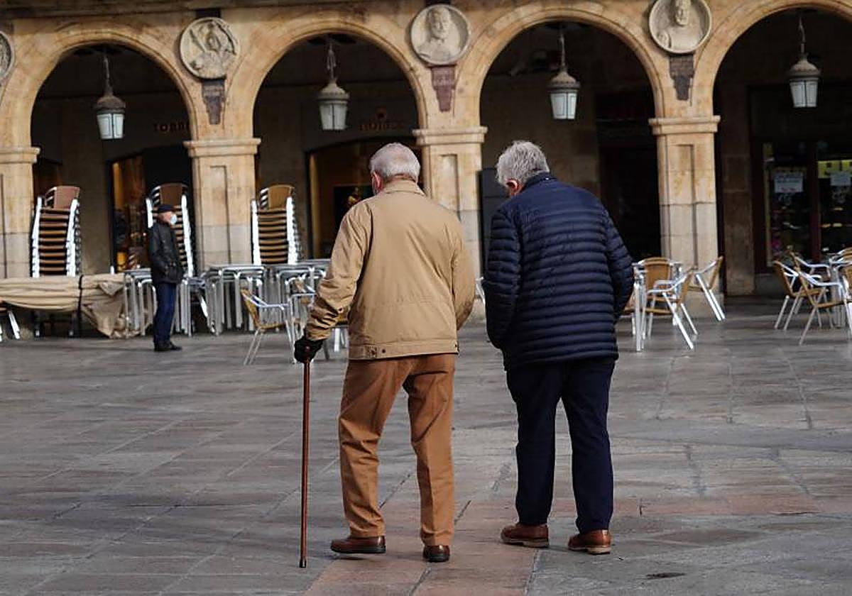 Dos personas mayores pasean por la Plaza Mayor de Salamanca.