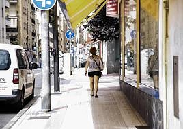 Una mujer camina bajo la sombra de un toldo.