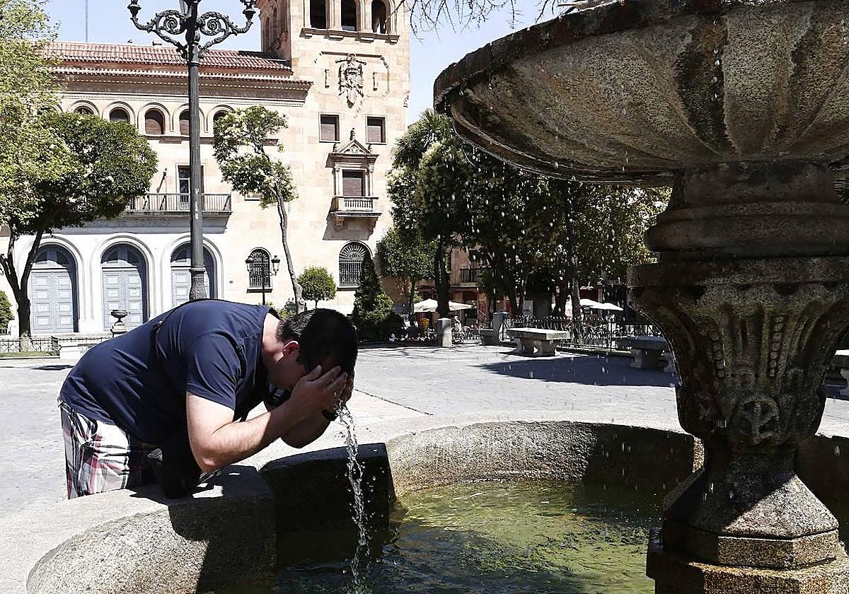 Un joven se refresca en la fuente de la Plaza de los Bandos de Salamanca para mitigar el calor en Salamanca.