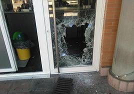 Imagen de la puerta de un local comercial rota con una tapa de alcantarilla para entrar a robar.