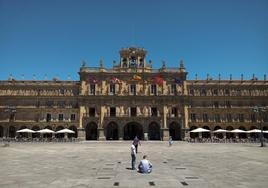 Un hombre sentado en el medio de la Plaza Mayor de Salamanca en las horas centrales de un día de este mes de julio.