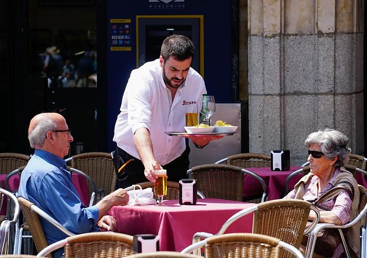 Un camarero atiende a pos personas en una terraza de Salamanca.