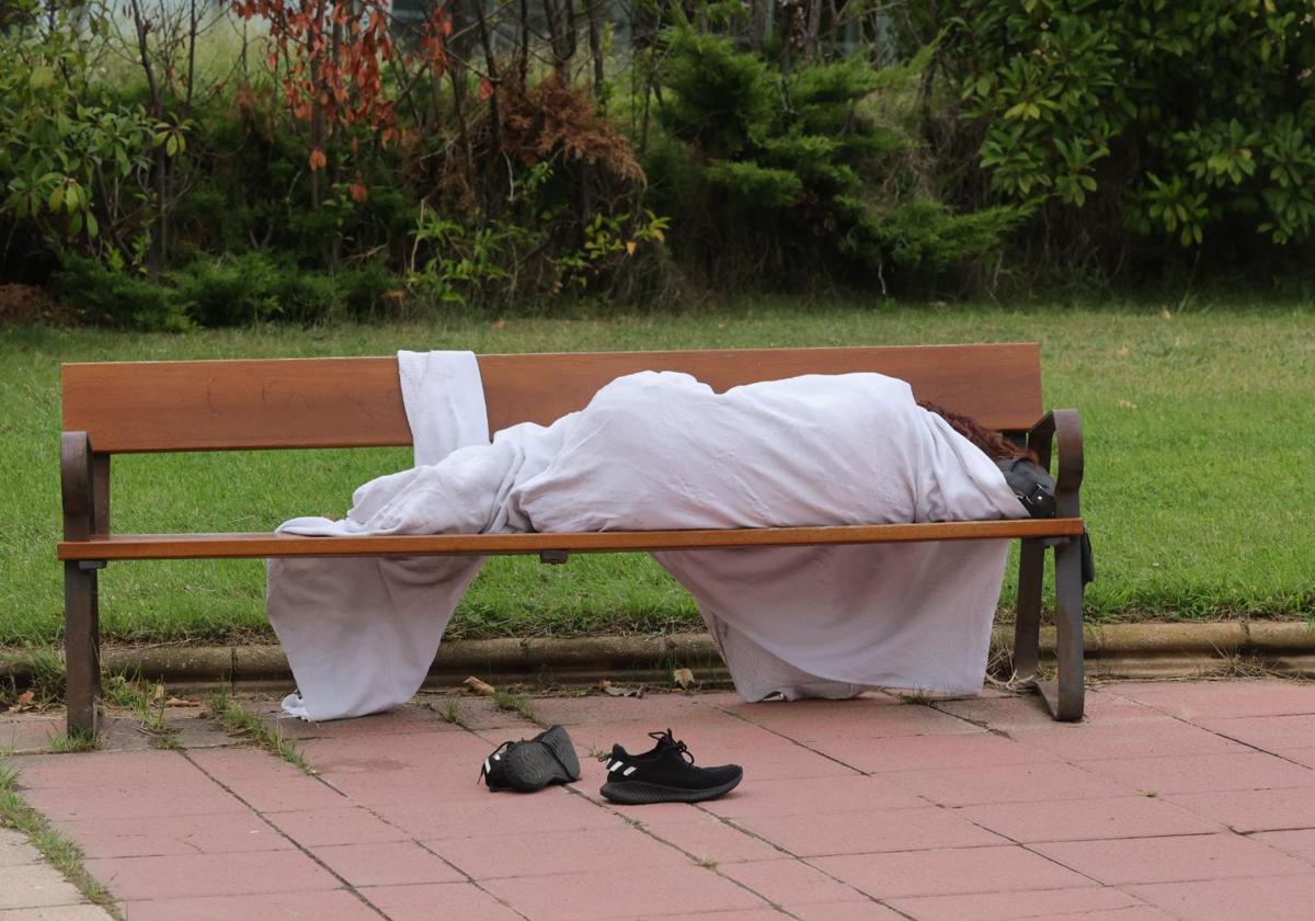 Mujer envuelta con una sábana sobre un banco.