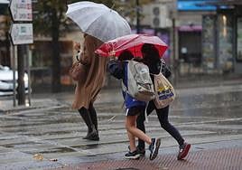 Dos niños tratan de protegerse del viento y de la lluvia.