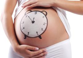 Una mujer embarazada con un reloj dibujado en el vientre.