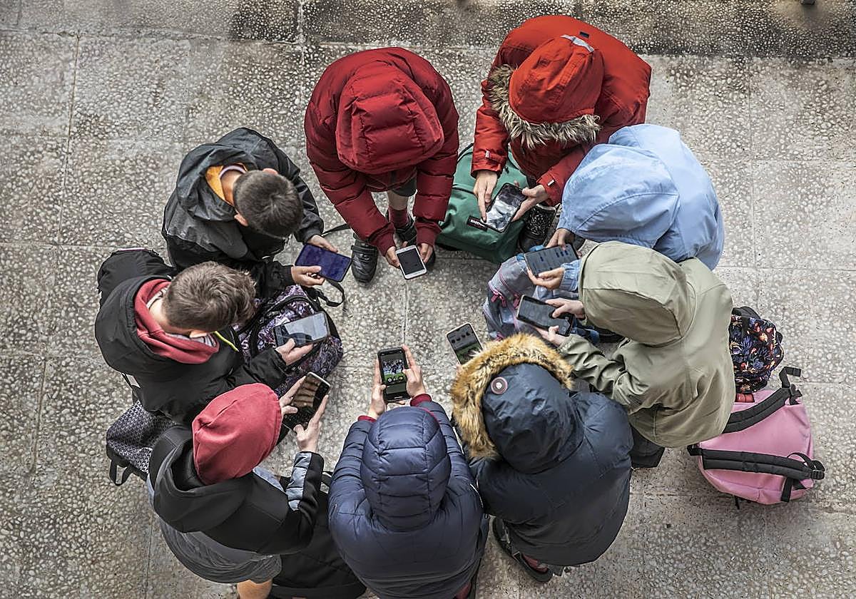 Un grupo de jóvenes en torno a sus móviles y dispositivos.