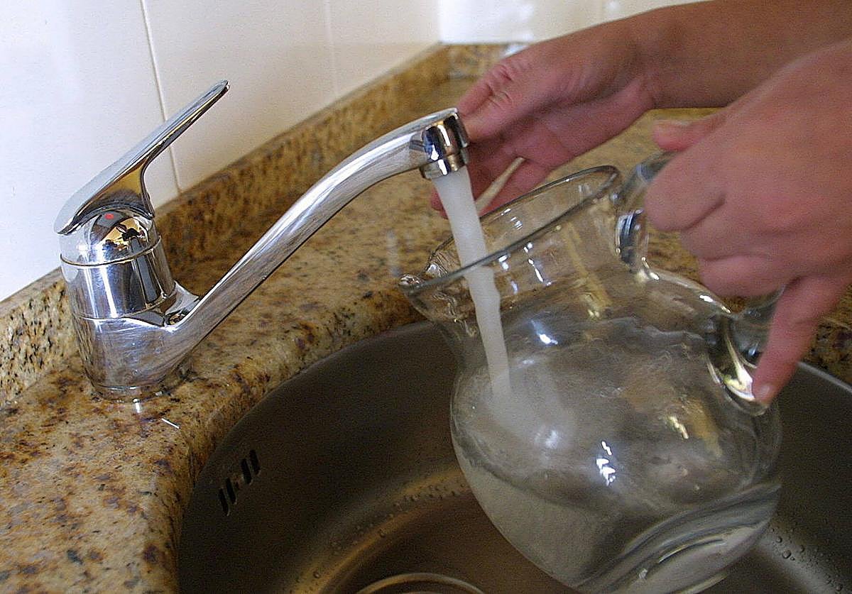 Una persona recoge agua en una jarra.