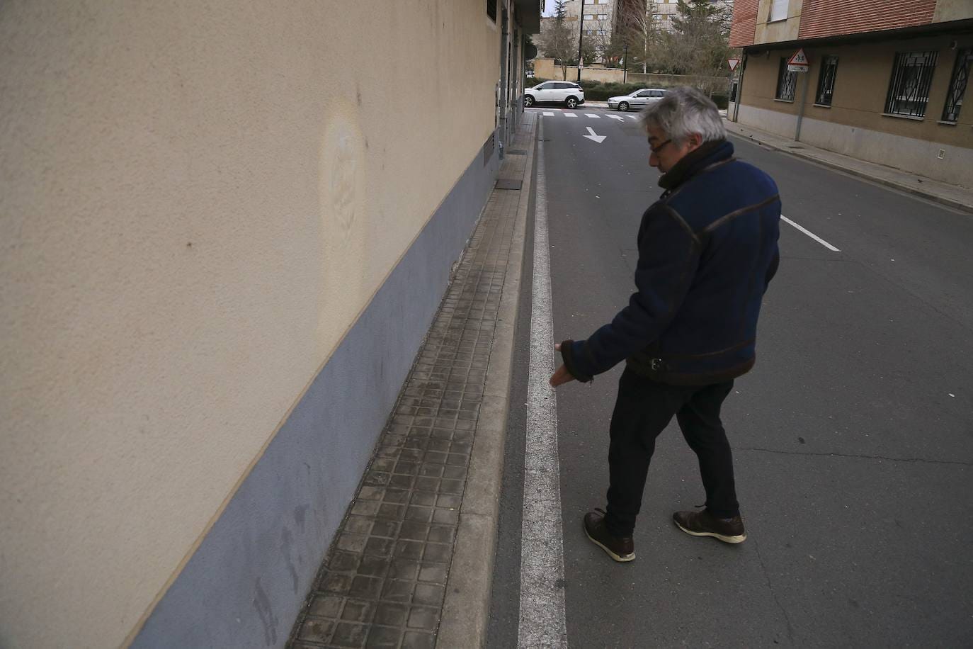 Imagen principal - Arriba, el presidente la asociación de vecinos, señala la que podría ser la acera nás estrecha de la ciudad.