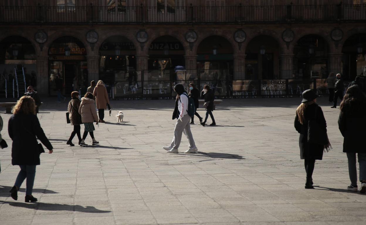 Viandantes caminando por la Plaza Mayor en un día soleado en Salamanca.