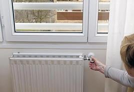 Una mujer manipula un radiador de la calefacción.