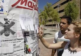 Dos estudiantes observan anuncios de pisos y habitaciones en el campus Unamuno de Salamanca.