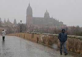Varios ciudadanos pasean por el Puente Romano el pasado sábado durante la nevada.