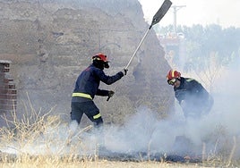 Dos bomberos sofocan un incendio por la quema de rastrojos.