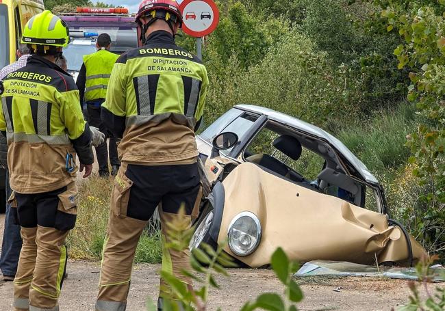 Los bomberos, junto al coche siniestrado.