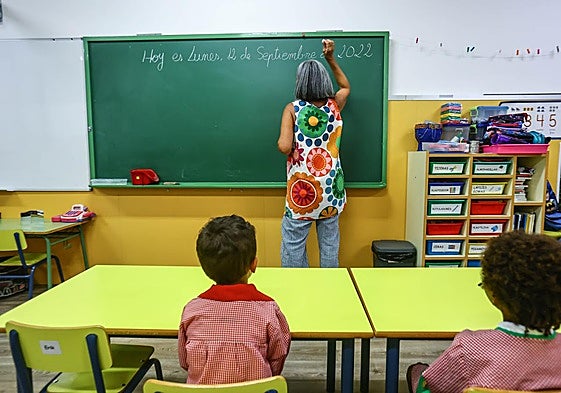 Una maestra escribe en la pizarra durante una clase.