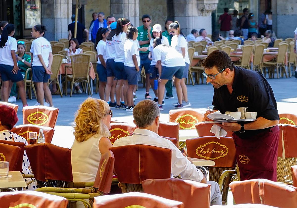 Un camarero atiende a unos clientes en una terraza de la Plaza Mayor.